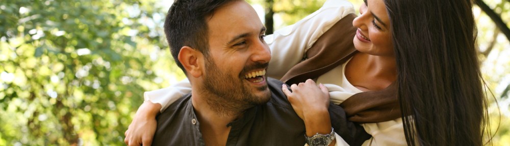 Boyfriend carrying his girl trough city park.